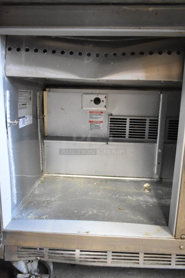 Beverage Air SPE48-18M-HMP stainless steel prep table interior, showing commercial casters and ventilation with visible wear.