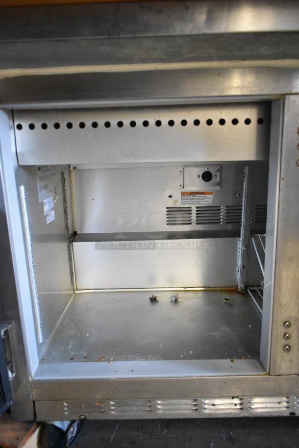 Beverage Air stainless steel prep table interior with shelving, electric components, and visible wear. Suitable for commercial use.