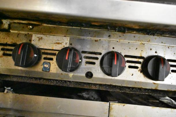 MagiKitch'n stainless steel gas-powered charbroiler grill with control knobs, visible wear, NSF label.