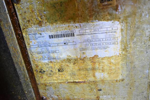 Pitco Frialator SG14 deep fat fryer label shows model, 110,000 BTU, natural gas, and cleaning instructions on a worn surface.