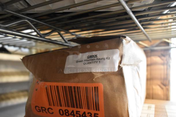 Brown paper package labeled "GMKK Green Mountain Keurig Kit Quantity 1" on a metal shelf. Barcode visible.