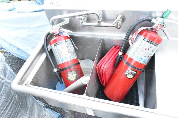 Stainless steel 2 bay sink with right side drain board and two Buckeye fire extinguishers placed inside.