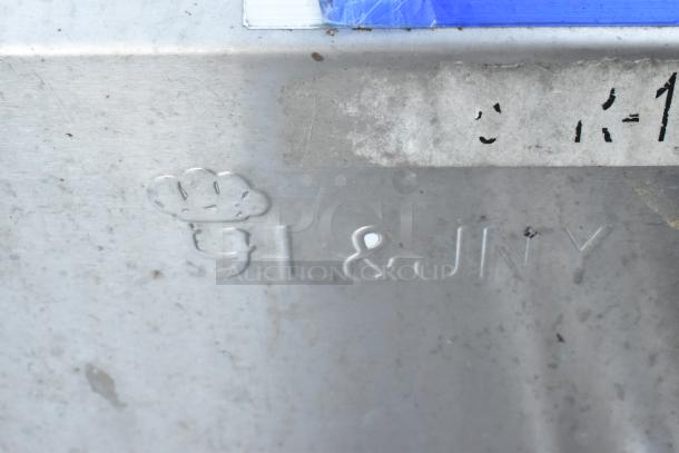 Stainless steel plate with embossed "GL & JNY" logo and partial model markings. Slight wear visible.