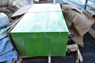 Green metal recycling bin shell on commercial casters, wrapped in plastic. Set on a pallet with cardboard packaging.