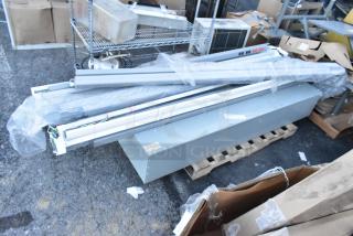 18 various items including light fixtures and a gray metal unit on a pallet. Some are wrapped in plastic. Condition appears used.