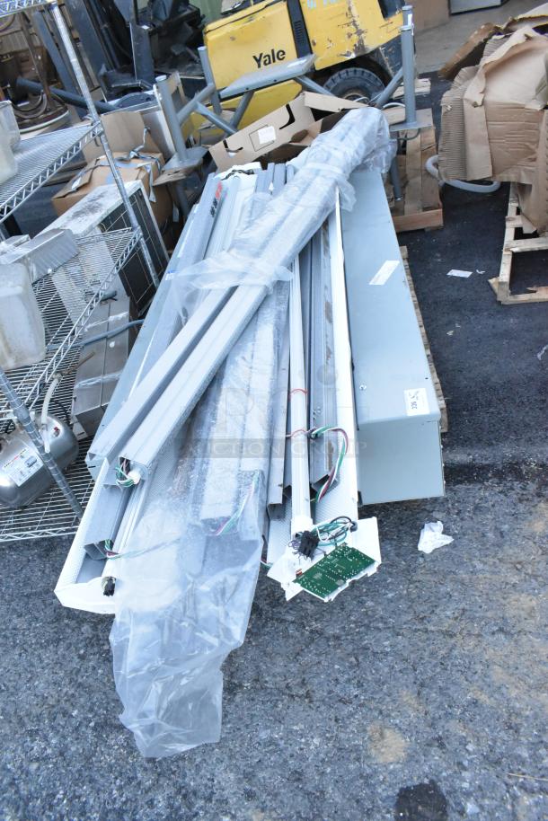 Bundle of 18 items including gray metal light fixtures, in used condition, shown on a pallet amidst packaging materials.