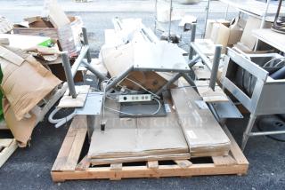 Table/booth setup components on a pallet, including metal frames, wiring, and boxed parts. Condition appears used.