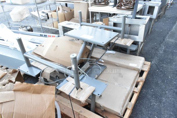Two-piece table/booth set in packaging on pallets, featuring metal frames. Items are in good condition, ready for setup.