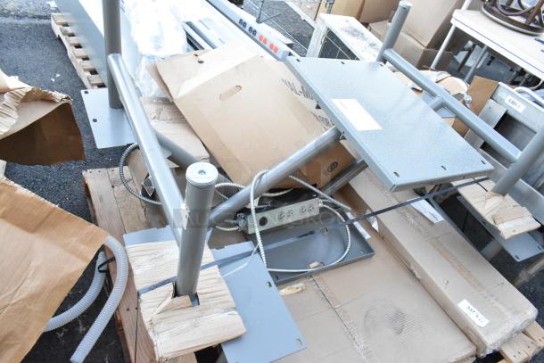 Metal table/booth setup components on pallets with wiring and cardboard packaging; potential for two setups.