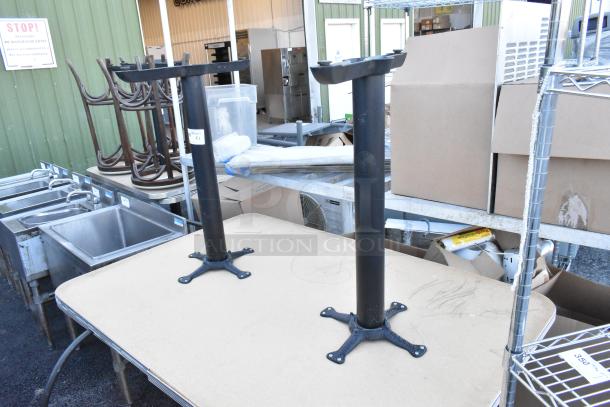 Two metal table bases with square mounting plates, shown outdoors. Marking indicates "2 Times Your Bid."