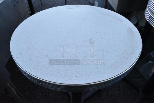 Round table with speckled white top on black metal base, stack of six. Good condition, ideal for dining or events.