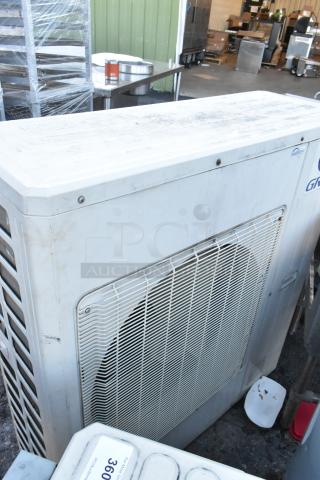 Gree metal outdoor unit for split-type air conditioner, used, with visible wear and dirt. "Gree" logo and "Inverter" label present.