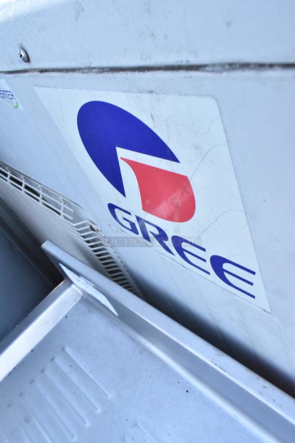 Gree metal outdoor unit for split air conditioner, features brand logo, visible wear, sturdy construction.
