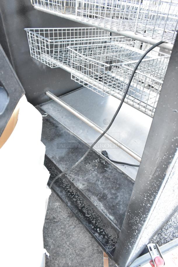 Vulcan 1013776 metal commercial bakery display rack with wire baskets, on commercial casters. Visible wear and electrical cord.