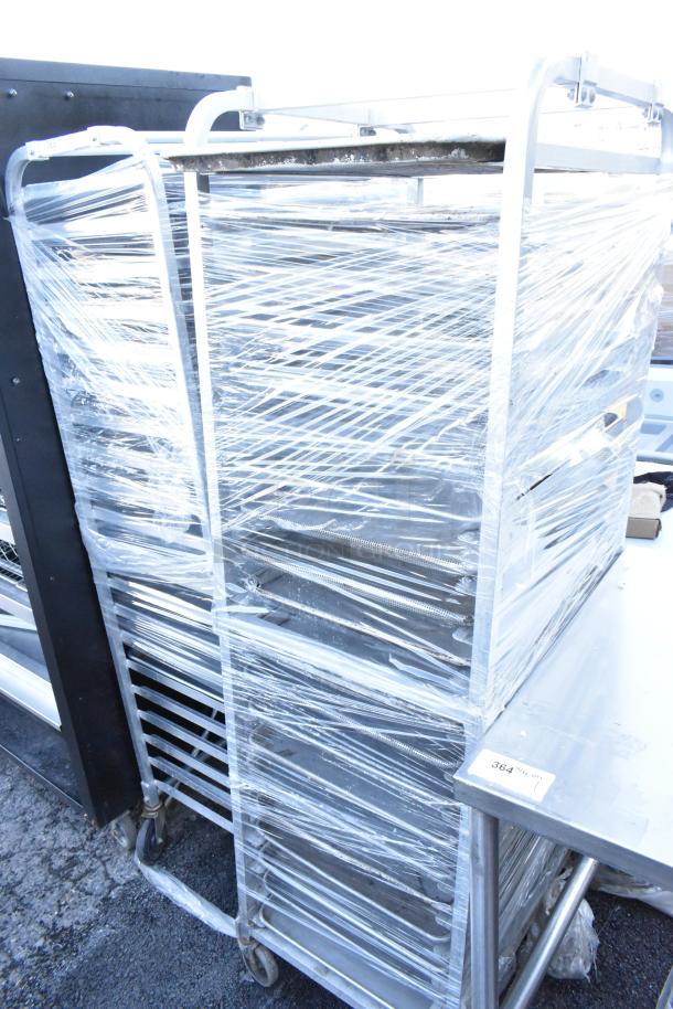 Two metal commercial pan transport racks on casters, wrapped in plastic, sturdy and ideal for catering or bakeries.