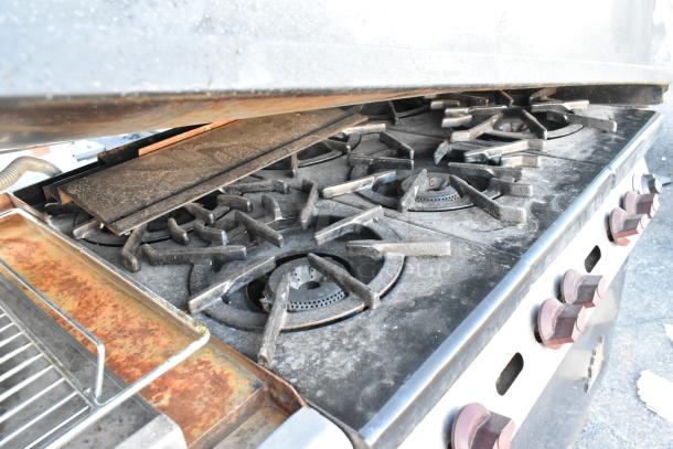 Wolf commercial gas range with 6 burners, flat top griddle, oven, backsplash, and overshelf. Used condition.