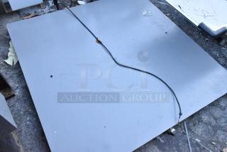 Gray metal panel featuring a hole, visible cable, and minor surface marks. Condition suggests use; ideal for industrial applications.