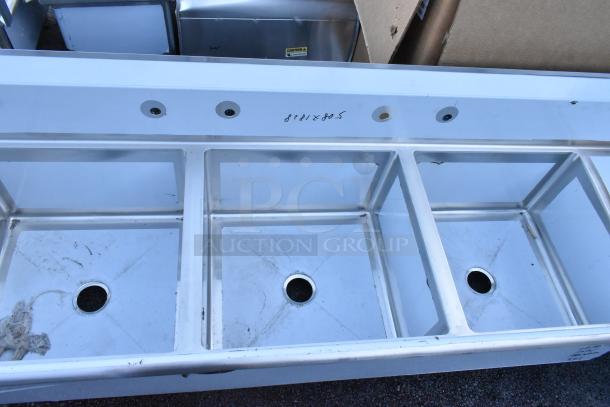Brand new Regency stainless steel 3 bay sink with dual drain boards, no legs. Visible scratches and dents, model marked “872 x 805.”