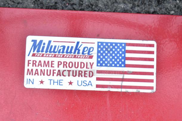 Milwaukee red metal hand truck with "Frame Proudly Manufactured in the USA" label. Ideal for heavy lifting.