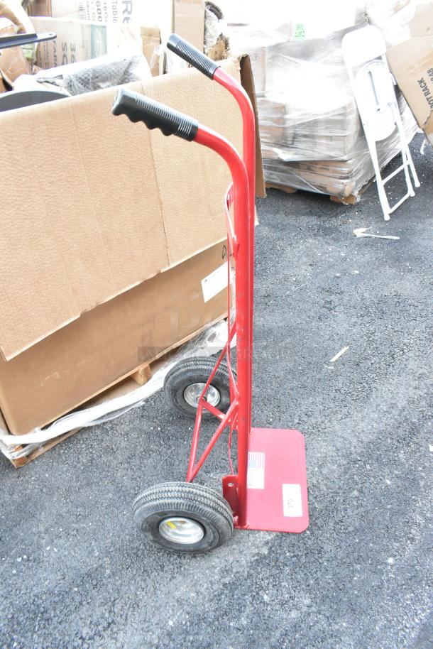 Milwaukee red metal hand truck, rubber grip handles, pneumatic wheels, sturdy construction, slight wear, model tag visible.