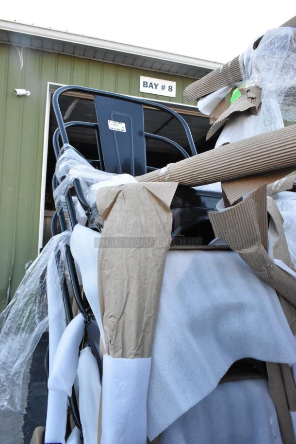 Stack of scratch and dent chairs in packaging, alongside a work table. Items are newly manufactured but imperfect.