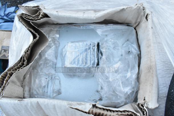 Box containing five new scratch and dent black poly shelf pieces, wrapped in plastic and stored in protective packaging.