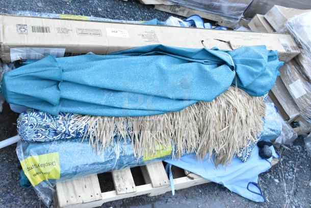 Pallet lot featuring a blue patio umbrella and assorted items, including a straw mat, displayed on wooden pallet. Various packaging visible.