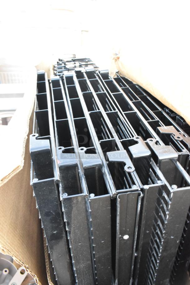 Pallet lot of brand new black metal wire racks with minor scratches and dents, stacked on cardboard packaging.