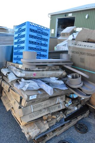 Stack of boxed items including table bases, cocktail tables, some with visible scratches and dents. Blue racks on top. Markings indicate dimensions and origin.