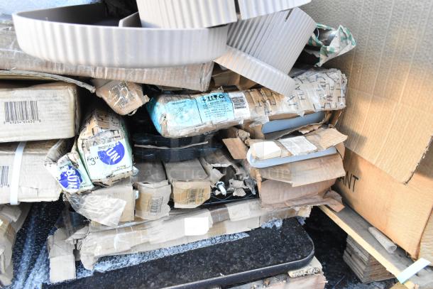 Stack of cardboard boxes containing various new scratch and dent items, including table bases and cocktail tables. Boxes show wear.