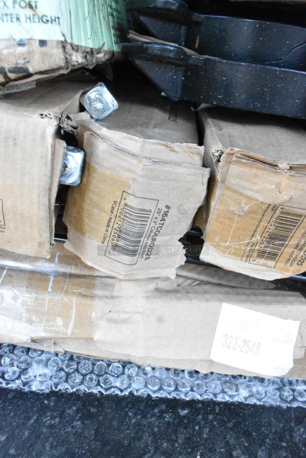 Stack of damaged boxes containing table bases and cocktail tables, labeled with barcodes and model #16ATCQR0025.