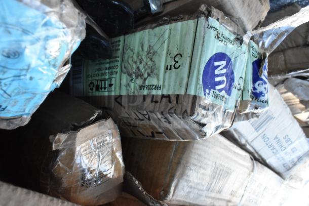 A pile of new, scratch-and-dent items in damaged packaging, includes table bases and cocktail tables. Visible labels provide handling instructions.