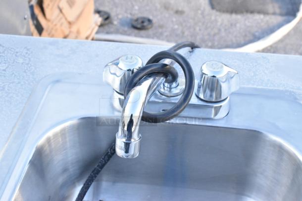 Stainless steel portable sink with chrome faucet and dual knobs on commercial casters; durable and functional design.