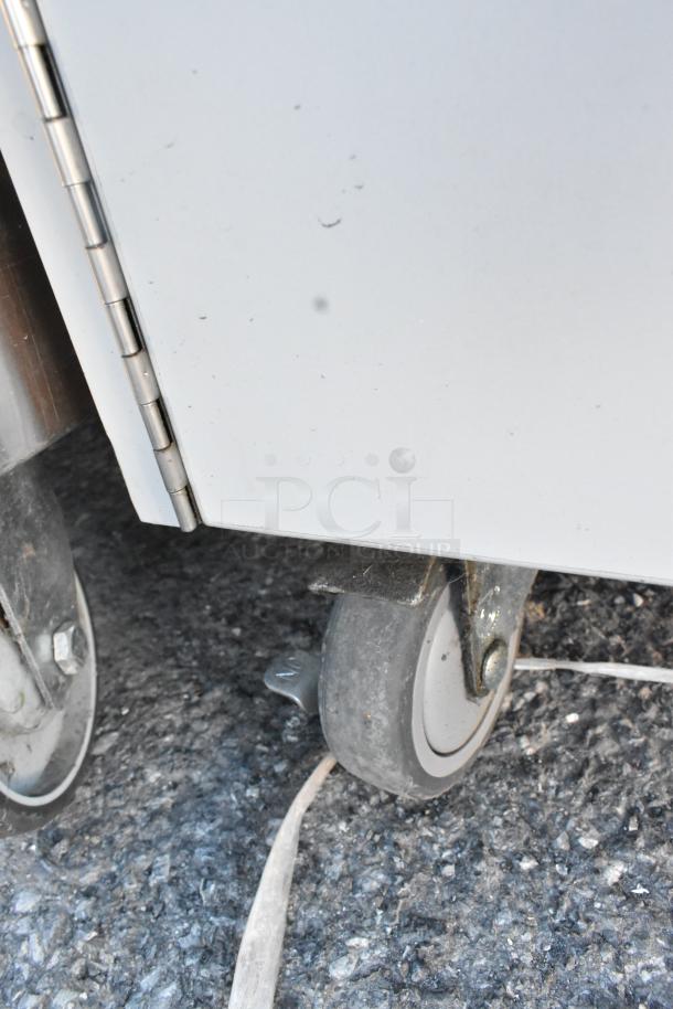 Stainless steel portable sink with commercial casters shown; durable design, slight wear visible.