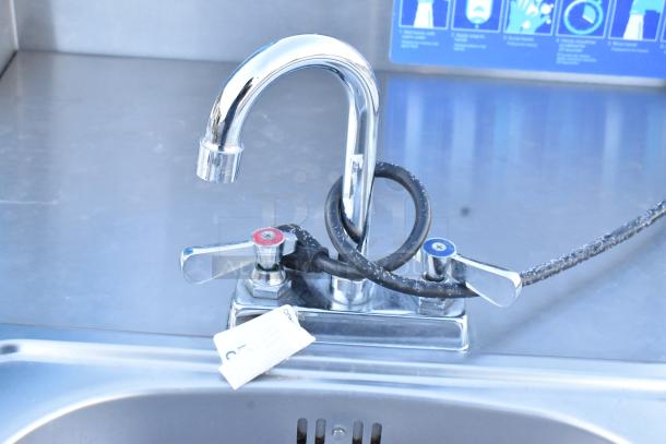 QualServ stainless steel portable sink with faucet, dual handles, commercial casters, 120V, 1 phase, instruction label visible.