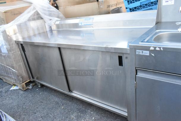 Win-holt stainless steel counter with two sliding doors, under shelf, and commercial casters. Good condition. Suitable for commercial use.