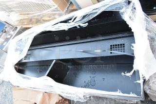 Black metal locker, partially wrapped, showing shelving and vented sections. Appears in used condition with visible water spots.