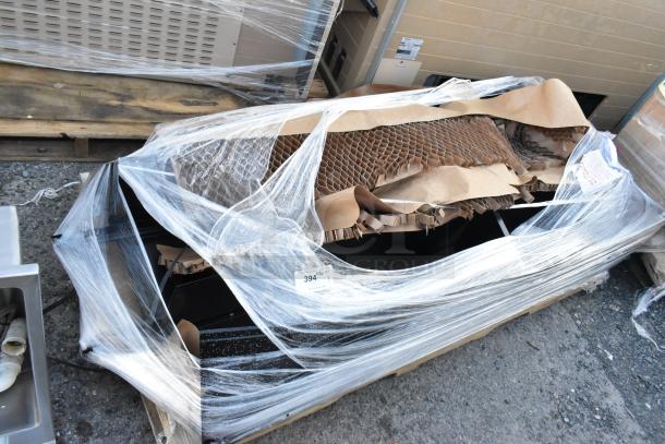 Black metal locker wrapped in plastic and packing material. Appears new with visible auction tag marked "394."