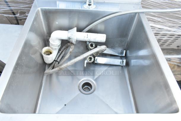Universal stainless steel single bay foot pedal sink with visible plumbing components. Shows moderate use.