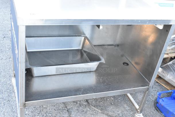 Stainless steel table with under shelf, drawer, and commercial casters. Includes metal tray. Durable and suitable for commercial use.