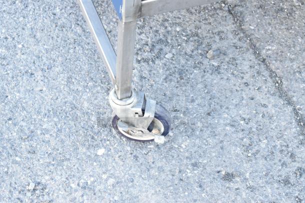 Stainless steel table leg on a commercial caster, featuring a locking mechanism, suitable for mobility and stability.