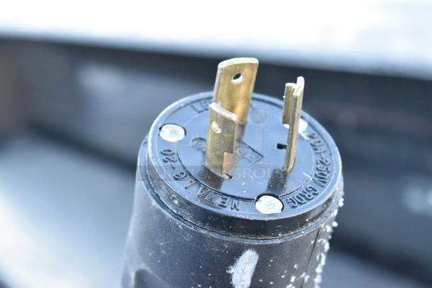 Close-up of a power plug labeled NEMA L6-20, 250V, with three prongs, used for commercial equipment.