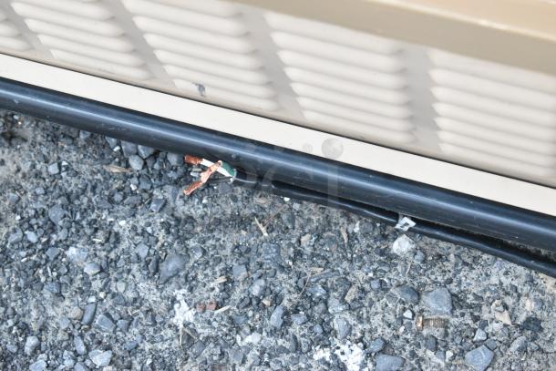 Killion PFW-74-43-48-V-N-MOBILE metal commercial merchandiser, shown from side with visible wiring, on gravel.