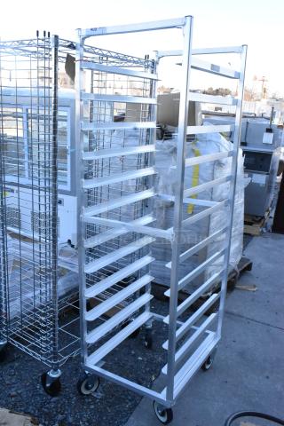 Metal commercial pan transport rack with multiple slots, on heavy-duty casters, suitable for bakery or restaurant use.