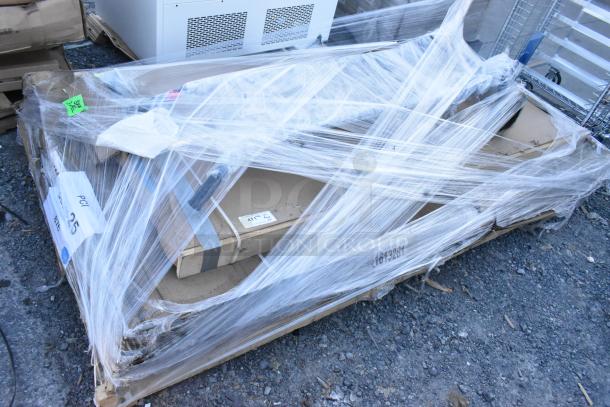 Pallet with four new items, including a portable stage and traffic door, wrapped in plastic with visible labels.