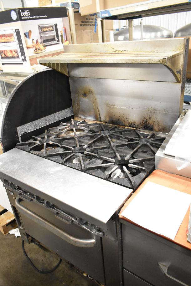 Southbend commercial stainless steel gas range with 6 burners, oven, and backsplash. Visible wear, ideal for high-volume kitchens.