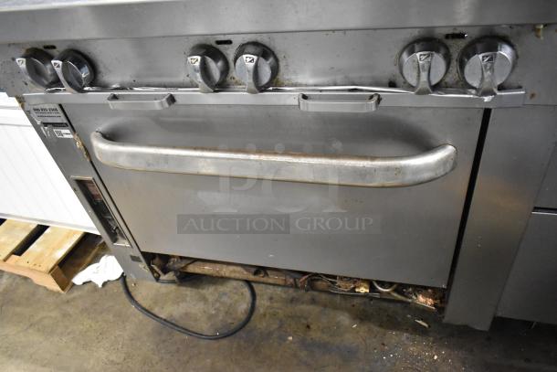 Southbend stainless steel commercial gas range, 6 burners, oven, back splash, visible wear, ideal for high-capacity kitchens.