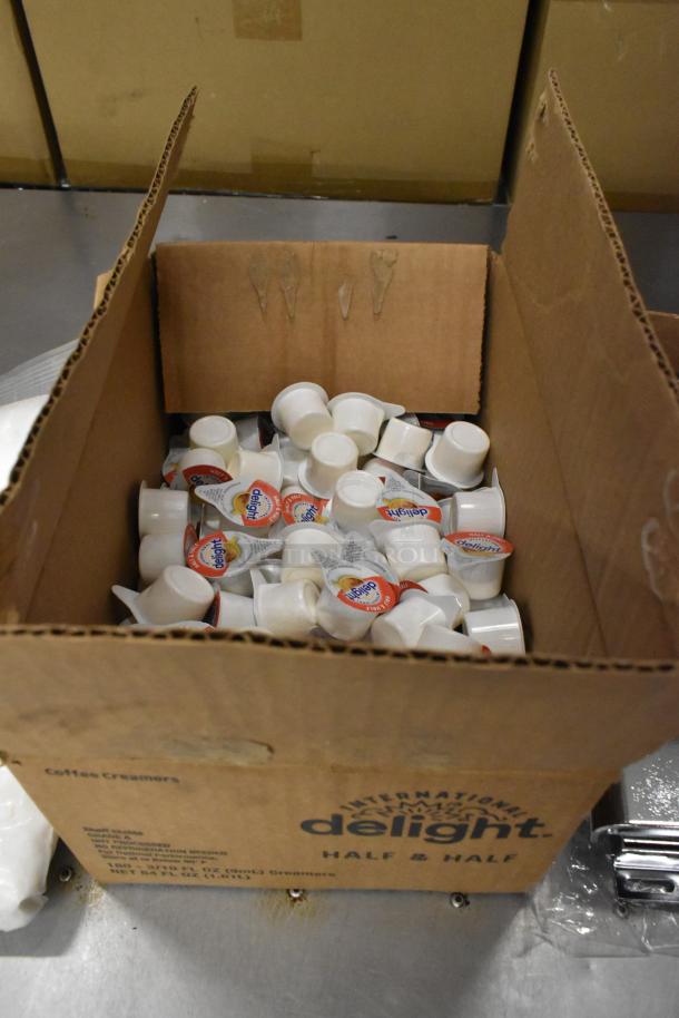 Box of International Delight Half & Half creamers, filled with multiple individual containers. Box labeled for coffee creamers.