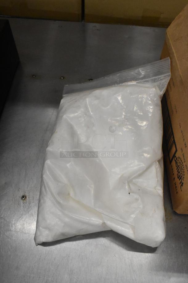 A sealed plastic bag on a metal surface next to a cardboard box. Condition appears new. No visible labels or markings.