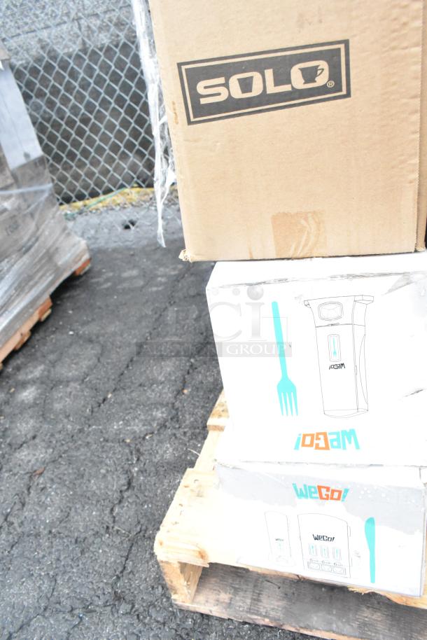 Cardboard boxes labeled "SOLO" and "WeGo" on a pallet, indicating new scratch and dent items like bakery trays and utensils.